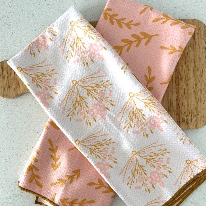 Set of three floral-patterned napkins on a wooden board.