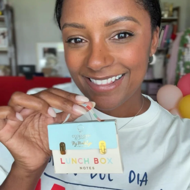 Person holding a product with 'Lunch Box Notes' text in a casual setting