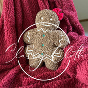 Red blanket with a gingerbread girl throw pillow on a couch.