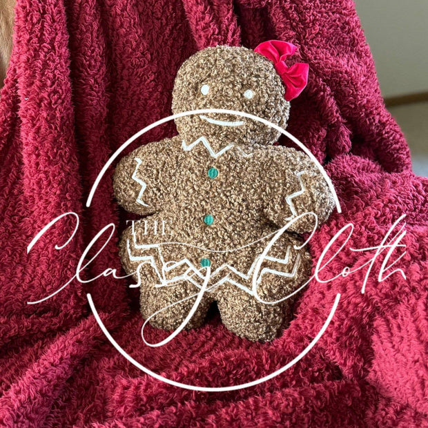 Red blanket with a gingerbread girl throw pillow on a couch.