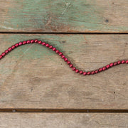 Red beaded string on a wood surface