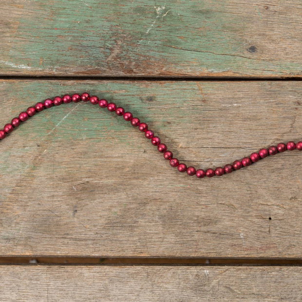 Red beaded string on a wood surface