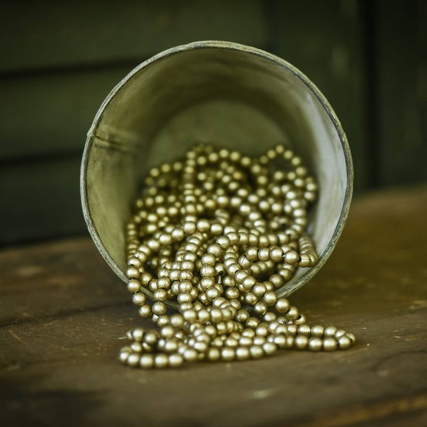 Metallic aged silver beads spilling out of a tipped-over container on a wood surface