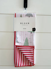 Packaged towel with red and white stripes and Christmas tree design on a white wooden background
