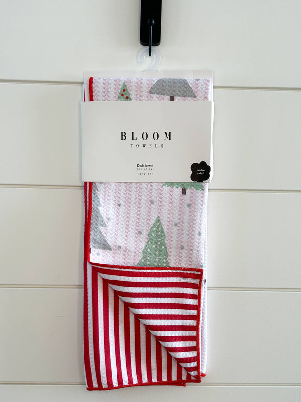 Packaged towel with red and white stripes and Christmas tree design on a white wooden background