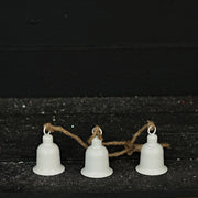 Three white bells on a string against a dark background