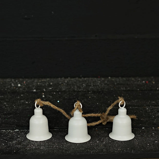 Three white bells on a string against a dark background