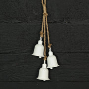 Three white metal bells hanging on a rope against a black wooden background