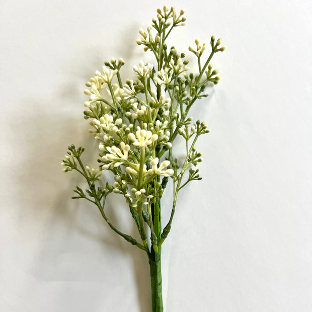 A single stem of artificial baby's breath with green leaves and white flowers.