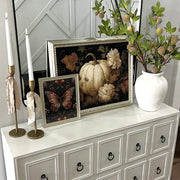 Decorative items on a white dresser including framed pictures, a vase with flowers, and candles.