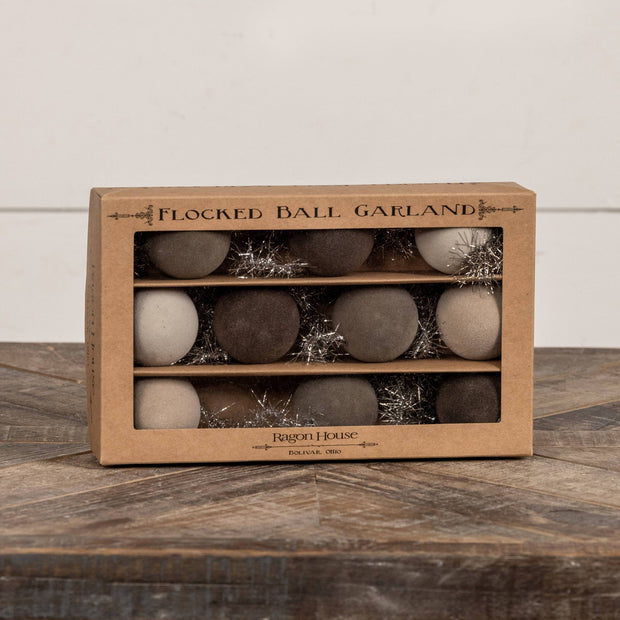 Box of flocked ball garland with decorative balls on a wooden surface