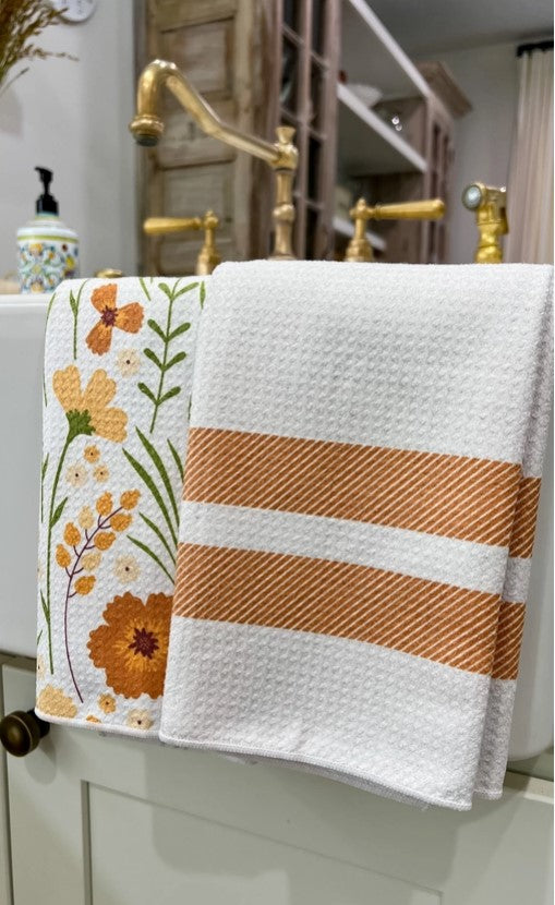 Decorative towel with floral design and stripes hanging on a bathroom rack.