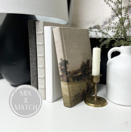 A flax linen book used as a decorative item on a shelf alongside other books, a lamp, and a small plant.
