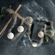 Two black gift boxes with decorative ribbons and ornaments on a dark surface.