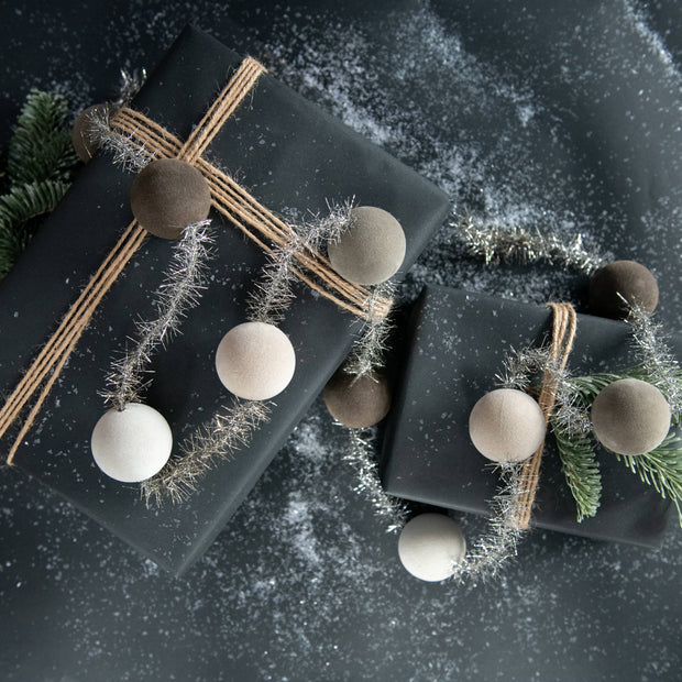 Two black gift boxes with decorative ribbons and ornaments on a dark surface.