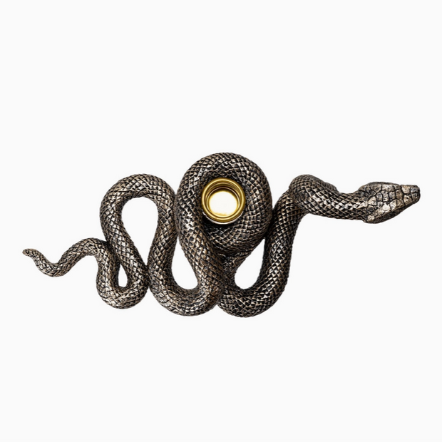 Serpent-shaped candle holder with taper candle on tabletop display