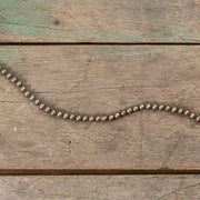 Metallic aged silver beaded garland on a wood surface