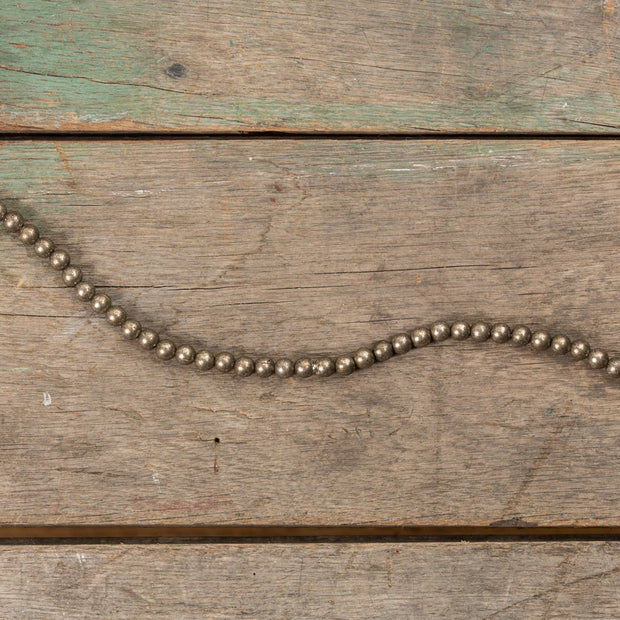Metallic aged silver beaded garland on a wood surface