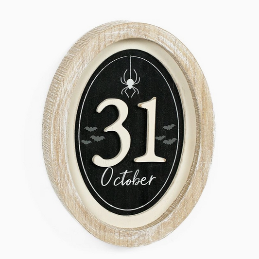 Decorative sign with '31 October' text and spider design on a black background, framed in beige.