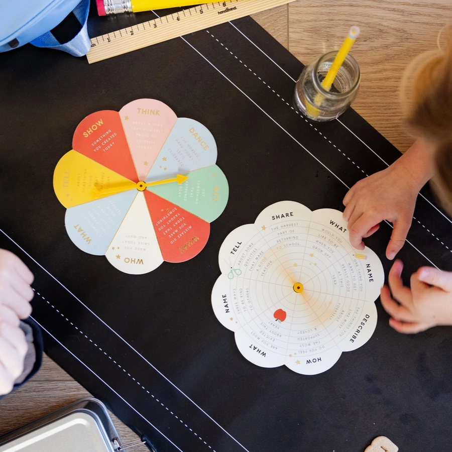 Colorful wheel chart on a black surface with a child's hand interacting with it.