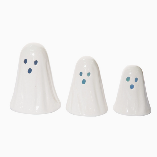 Three white ghost-shaped ceramic figures with blue eyes on a white background