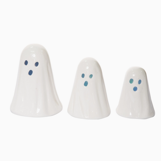 Three white ghost-shaped ceramic figures with blue eyes on a white background