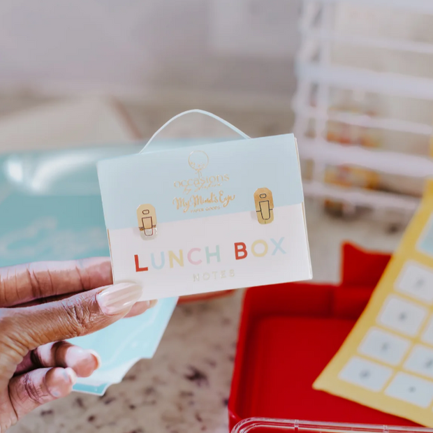Hand holding a lunch box label with colorful text and icons.