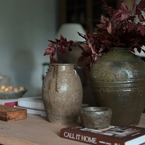 Two ceramic vases with a small bowl and book on a wooden surface.